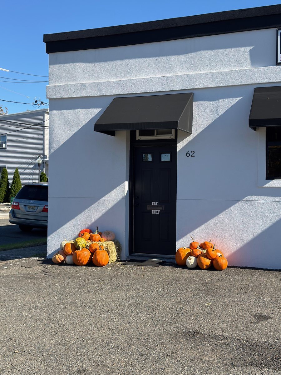 Storefront fall decorating at Elite Auto Haus in NJ: pumpkin displays on both sides of the entrance