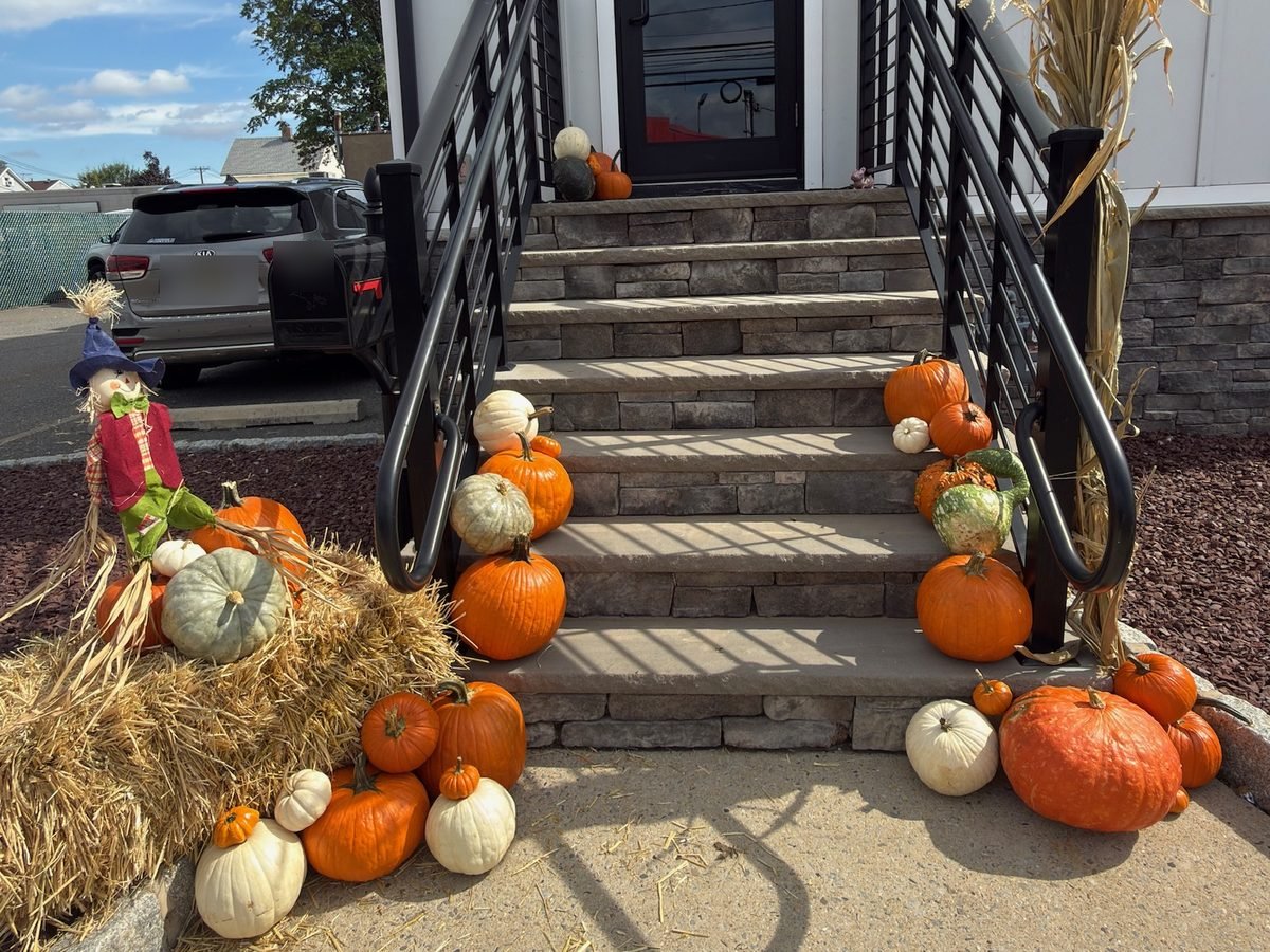 Real Doorstep package pumpkin display at an office entrance in Hackensack NJ, styled by Pascack Porches with a straw bale, scarecrow, and cornstalks