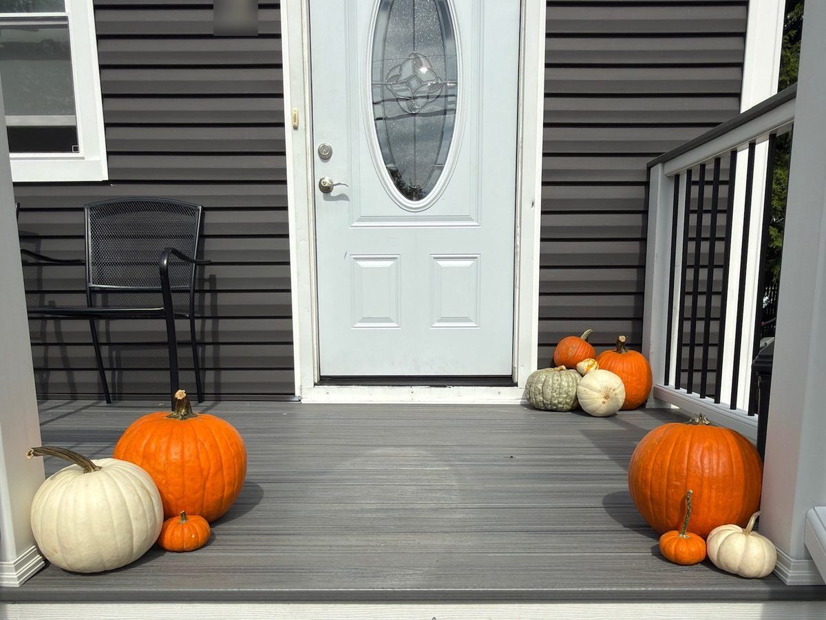 Fall porch decorating in Hackensack, NJ: pumpkins on both sides of a white front door