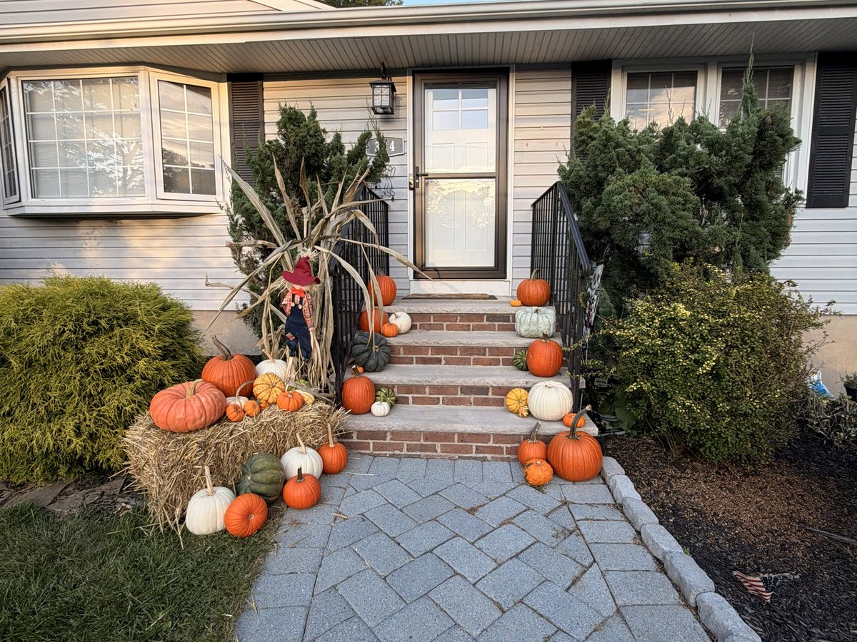 Real fall porch display in Hillsdale NJ, The Doorstep package styled by Pascack Porches with pumpkins, straw bale, cornstalks, and a scarecrow
